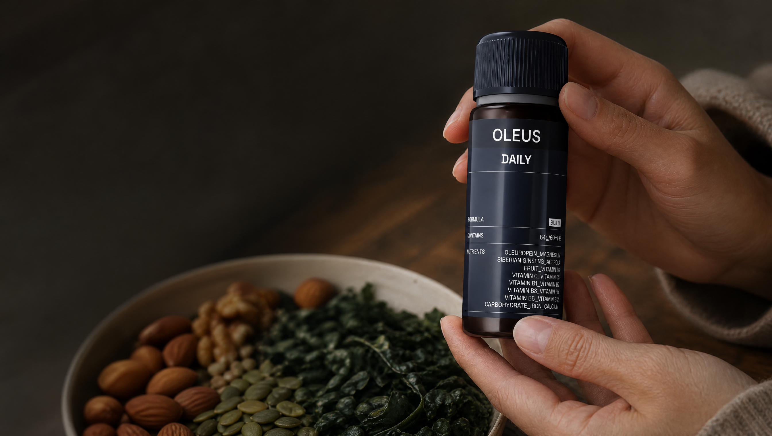 OLEUS Daily Shot beside a whole-food meal with leafy greens, fish, nuts, and fruit on a wooden kitchen table